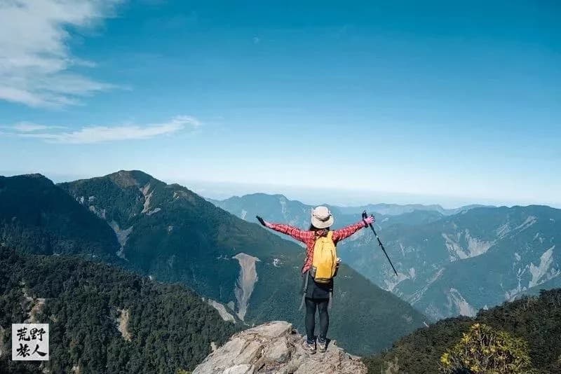山頂岩石上展臂眺望群山